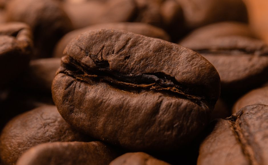 Detailed close-up image of roasted coffee beans with rich textures and dark brown tones.