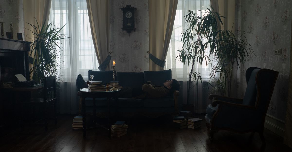 A dimly lit vintage living room featuring cozy furniture and candlelight ambiance.