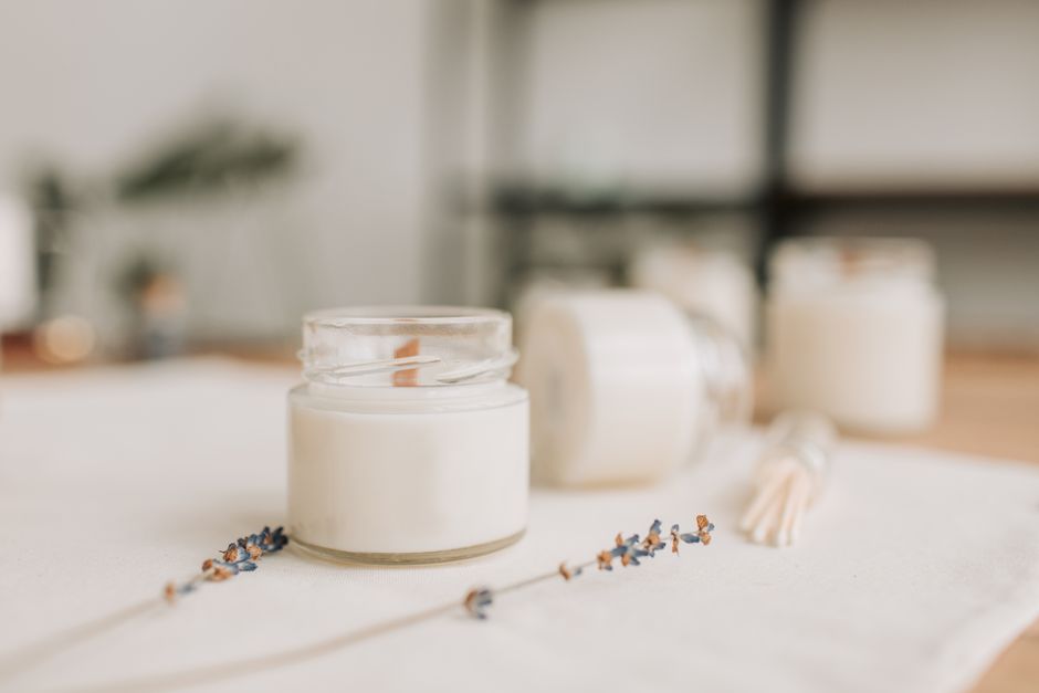 Warm and cozy candle setting with dried lavender and wax jar, perfect for a serene atmosphere.
