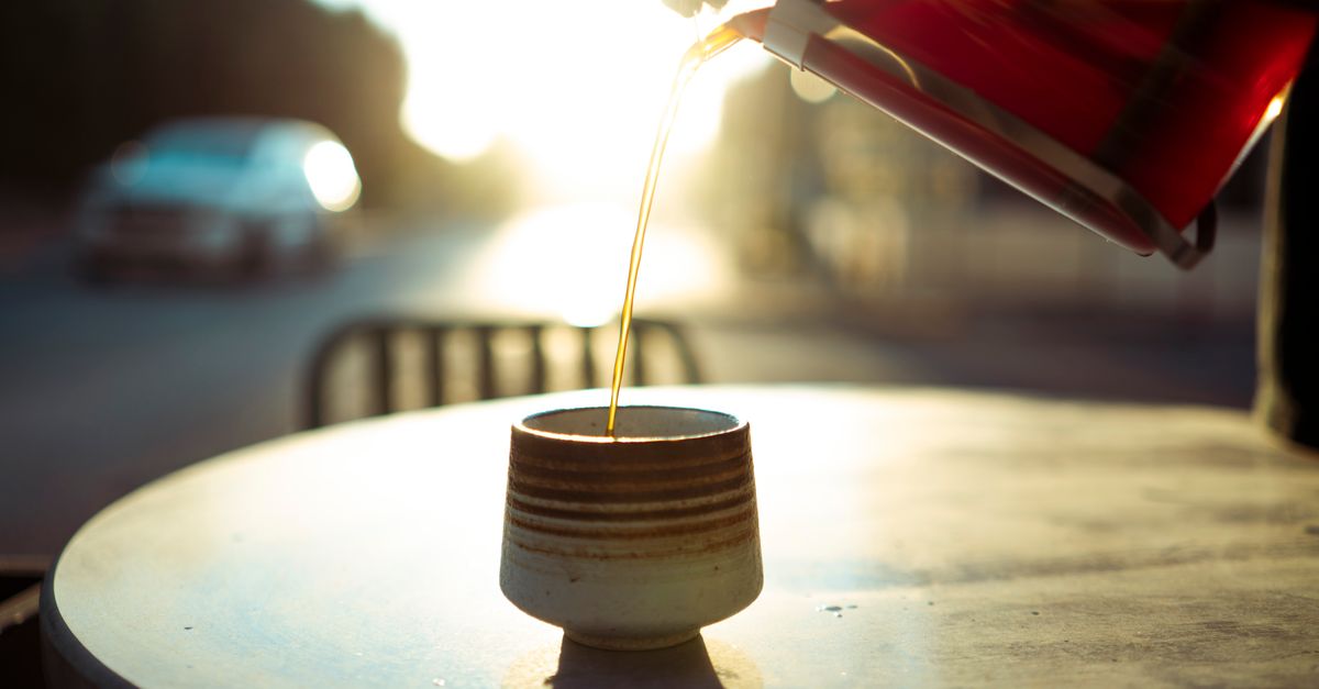 Warm morning light as coffee is poured into a cup at an outdoor cafe table in Baghdad.