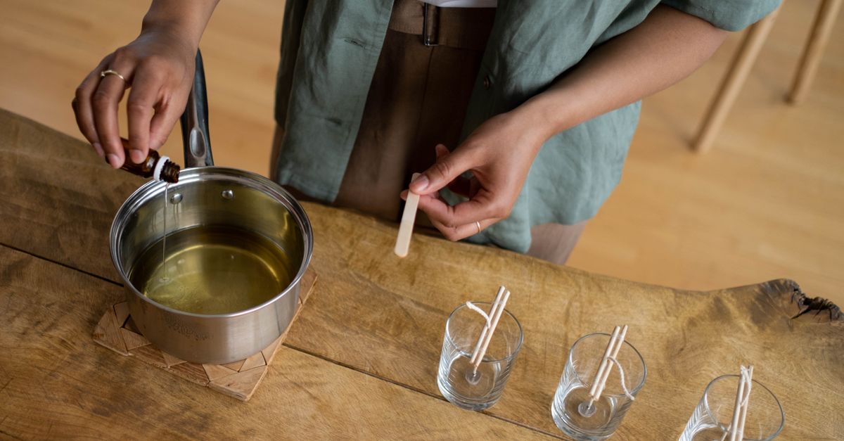 Close-up of candle making process with essential oils and wicks on a wooden table.
