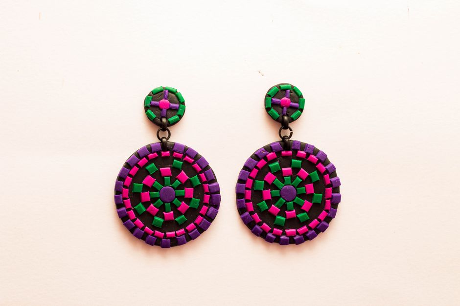 Vibrant round earrings with green, pink, and purple mosaic design on a minimalist white background.