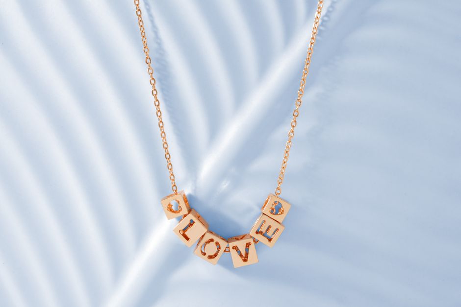 Elegant gold love pendant necklace with minimalist design on a white background.