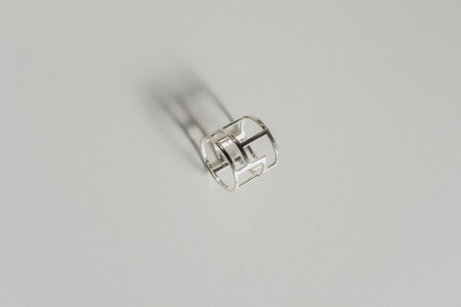 Simple silver ring casting a shadow on a white surface, showcasing minimalistic design.