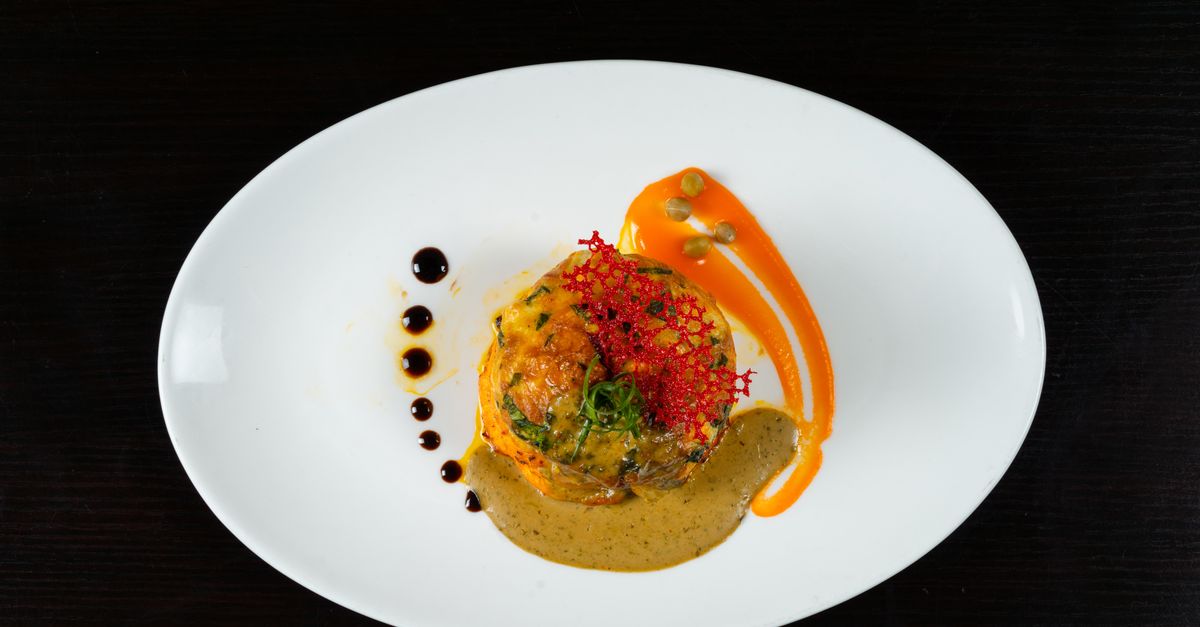 Gourmet seafood dish elegantly plated with vibrant sauces and herbs on a white plate.