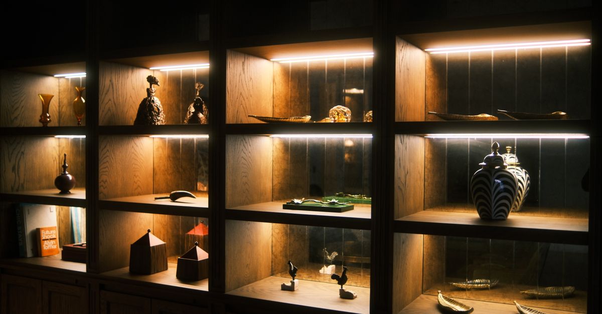 Wooden display shelves with artistic ceramics and sculptures elegantly lit for a warm ambiance.