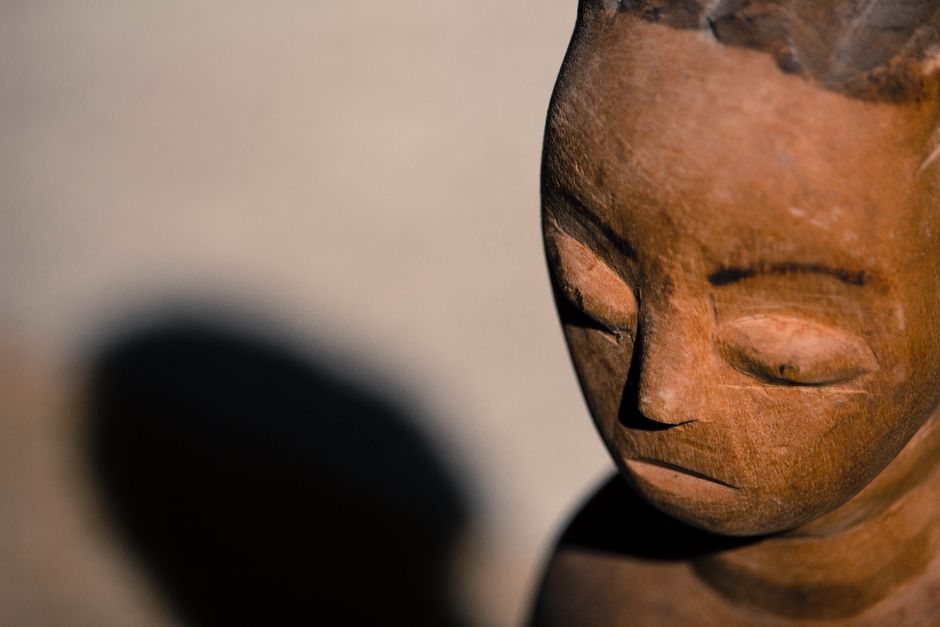 Detailed photo of a wooden sculpture head showing texture and shadow play.