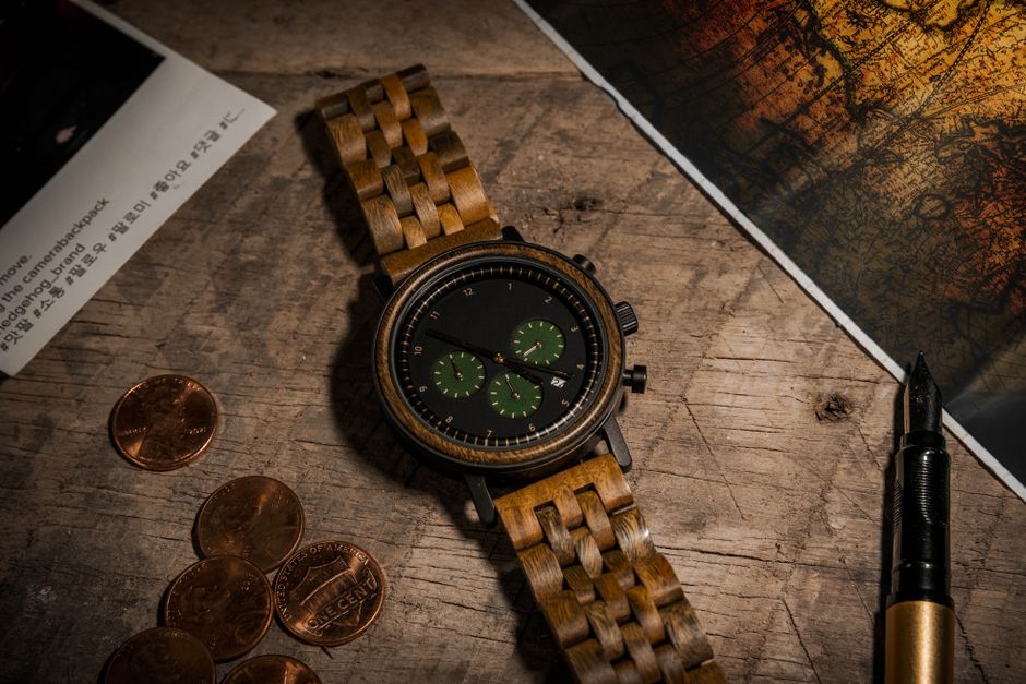 Stylish wooden wristwatch with coins and fountain pen on rustic wooden surface. Ideal for lifestyle and product photography.